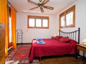 Schlafzimmer mit einem roten Bett und einem Deckenventilator in der Unterkunft Villa Villa Ute by Interhome in Les tres Cales