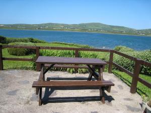a wooden bench sitting next to a fence next to the water at Holiday Home Seaside Cottages-1 in Valentia Island