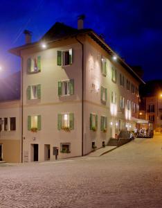 a large white building with green shuttered windows at night at Albergo Tuenno in Tuenno