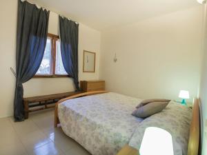 sypialnia z łóżkiem i oknem z niebieskimi zasłonami w obiekcie Apartment Casina by Interhome w mieście Porto Azzurro