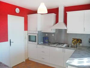 a kitchen with white cabinets and a red wall at Holiday Home Roumagnac by Interhome in Cavalaire-sur-Mer