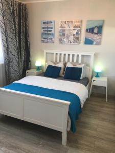 a bedroom with a white bed with blue sheets and two lamps at Mieszkanie 3 Maja in Sopot