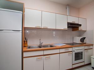 a kitchen with white cabinets and a sink and a refrigerator at Apartment Royal Delta-3 by Interhome in Riumar
