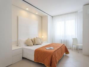 a white bedroom with a bed and a chair at Apartment Nautilus-6 by Interhome in San Salvo