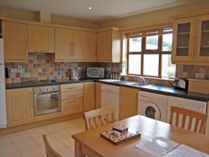 a kitchen with wooden cabinets and a wooden table with a tableablish at Holiday Home Ardgroom-1 by Interhome in Ardgroom