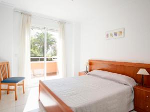 ein Schlafzimmer mit einem Bett, einem Fenster und einem Stuhl in der Unterkunft Apartment Keops by Interhome in Casas Devesa