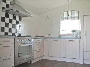 eine Küche mit weißen Geräten und einer karierten Wand in der Unterkunft Holiday Home Wiringherlant-7 by Interhome in Noordstroe