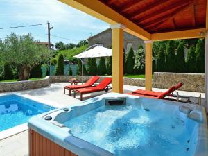 a hot tub on a patio with two chairs and an umbrella at Holiday Home Villa Olea by Interhome in Opatija