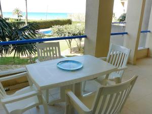 einen weißen Tisch und Stühle mit einem Teller drauf in der Unterkunft Apartment Las Dunas-4 by Interhome in Denia