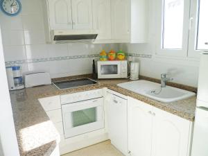 a white kitchen with a sink and a microwave at Apartment Club Sevilla I by Interhome in Casas Devesa