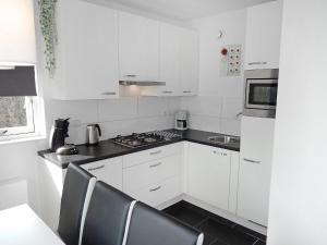 een keuken met witte kasten en een fornuis met oven bij Holiday Home de Witte Raaf-1 by Interhome in Noordwijk