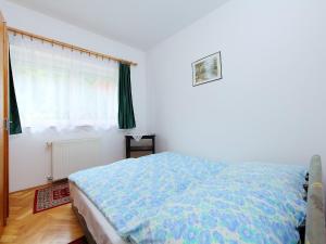 a bedroom with a bed with a blue comforter and a window at Holiday Home Greenie by Interhome in Balatonszárszó