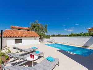a pool with two chairs and a table next to a house at Holiday Home Elena by Interhome in Raša
