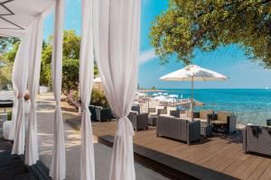 a patio with white umbrellas and chairs and the ocean at Hotel Coral Plava Laguna in Umag