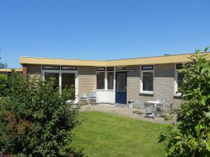 un edificio de ladrillo con patio, mesa y sillas en Holiday Home De Wijde Blick by Interhome, en Noordwijkerhout