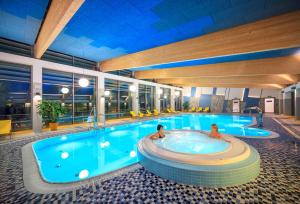 two people in a swimming pool in a hotel at Słoneczny Zdrój Medical Spa & Wellness in Busko-Zdrój