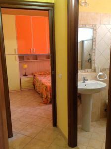 baño con lavabo y cama con armarios de color naranja en Villa Marco Polo, en Fanusa