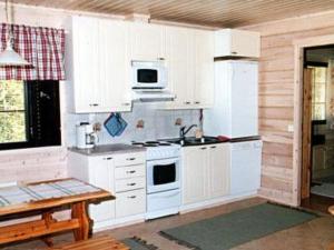 eine Küche mit weißen Schränken und einem Herd mit Backofen in der Unterkunft Holiday Home Mäntyaho by Interhome in Karvonen