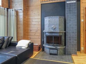 a fireplace in a living room with a black couch at Holiday Home Poronpurema a by Interhome in Levi