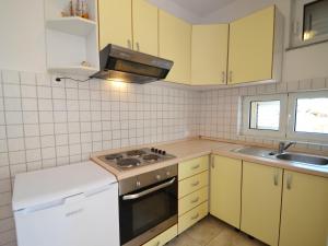 a kitchen with yellow cabinets and a stove and a sink at Apartment Golub-2 by Interhome in Cesarica