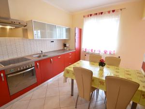 a kitchen with red cabinets and a table with chairs at Holiday Home Jelka by Interhome in Njivice