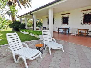 2 sedie bianche e un tavolo su un patio di Holiday Home Fiumara by Interhome a Margherita di Savoia