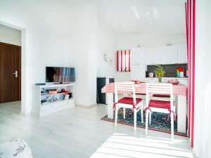 a white kitchen with a table and red chairs at Apartment Silvana-4 by Interhome in Matulji