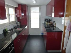 une cuisine avec des placards rouges et un comptoir noir dans l'établissement Apartment Hälmehois by Interhome, à Gerschnialp