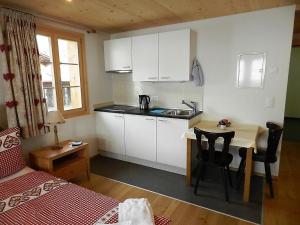 eine kleine Küche mit einem Waschbecken und einem Tisch mit Stühlen in der Unterkunft Apartment Mutthorn by Interhome in Lauenen