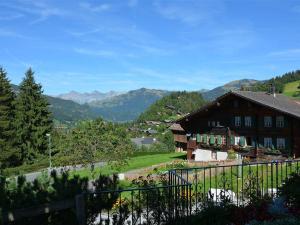 una casa su una collina con montagne sullo sfondo di Apartment Alegria - Parterre by Interhome a Gstaad