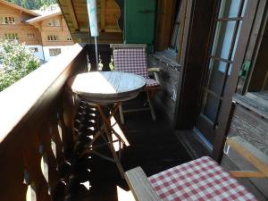 einen Balkon mit einem Tisch und Stühlen auf einer Veranda in der Unterkunft Apartment Im Wiesengrund by Interhome in Gstaad