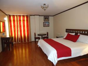 ein Schlafzimmer mit einem großen Bett mit einer roten und weißen Decke in der Unterkunft Hotel Plaza San Carlos in Xicotepec de Juárez