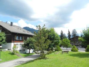 a park with a bench in the grass next to a building at Apartment Monique Nr- 14 by Interhome in Gstaad