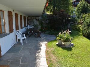 um pátio com uma mesa, uma cadeira e flores em Apartment Alegria - Parterre by Interhome em Gstaad