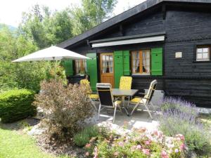 ein Haus mit einem Tisch, Stühlen und einem Sonnenschirm in der Unterkunft Apartment Abnaki- Chalet by Interhome in Gstaad