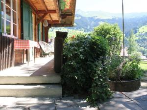 a building with a bush next to a sidewalk at Apartment Chalet Maru by Interhome in Lenk