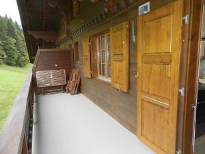 a porch with wooden doors and windows on a house at Apartment Hornflue - Baumann by Interhome in Gstaad