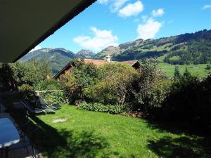 a view of a yard with a house and mountains at Apartment Am Ryschbächli by Interhome in Zweisimmen