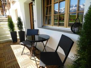 un patio con 2 sillas y una mesa de cristal en Apartment Bijou Arnensee by Interhome, en Gsteig
