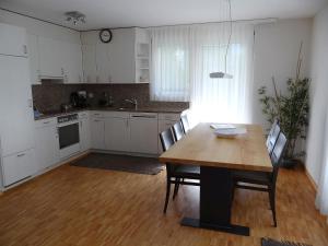 エンゲルベルクにあるApartment Rainstrasse 55 by Interhomeの白いキャビネット、木製テーブルと椅子付きのキッチンが備わります。