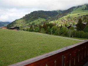 een uitzicht op een groen veld met een stad in de verte bij Apartment Mireille Nr- 8 by Interhome in Gstaad