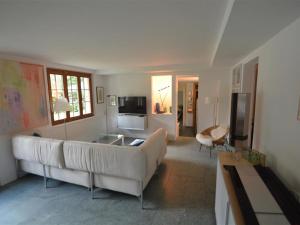 een woonkamer met een witte bank en een televisie bij Apartment Sambi by Interhome in Gstaad