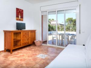a room with a bed and a tv and a balcony at Holiday Home Villa Santa Marta I by Interhome in Les tres Cales