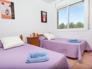 Habitación con 2 camas con sábanas moradas y ventana. en Villa Villa Mimosa I by Interhome en Les tres Cales