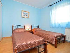 Cette chambre comprend 2 lits dans une chambre dotée de murs bleus et d'une fenêtre. dans l'établissement Apartment Cvjetko by Interhome, à Rakalj