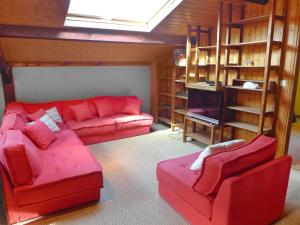 een woonkamer met een rode bank en planken bij Holiday Home Lac et Forêt by Interhome in Le Moutchic