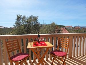 a table with two chairs and a bottle of wine on a balcony at Apartment Jasminka-1 by Interhome in Drage