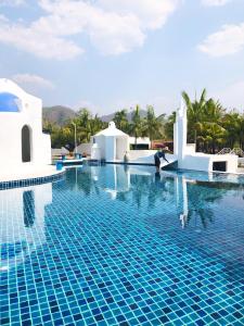 una piscina en un complejo con una persona parada en el agua en The Oia Pai Resort, en Pai