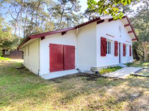 una pequeña casa blanca con puertas rojas y un patio en Holiday Home De la Plage by Interhome, en Labenne