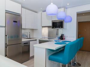a kitchen with white cabinets and blue chairs at Studio Dream View 50m from the beach by Interhome in Albufeira